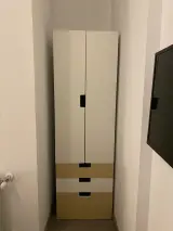 Interior apartment white two-door wardrobe with three wooden drawers beside a wall-mounted flat-screen TV